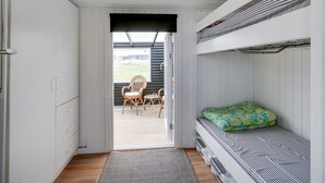 A compact room with a bunk bed, a small seating area with chairs, and a door leading outside. - "Adina" - 50m from the sea by Interhome (Hjørring)