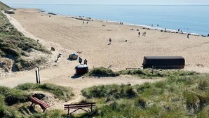 Een strand met een zandpad, een bankje en een wachthuisje.