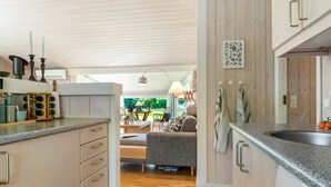 Een moderne keuken met houten kastjes, een ingebouwde vaatwasser en een eethoek met een tafel en stoelen.