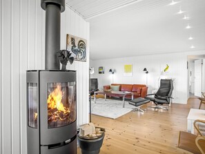 A modern living room with a wood-burning stove, a sofa, a coffee table, and a dining area.