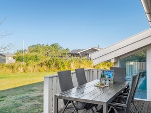 Eine Holzterrasse mit Tisch und Stühlen, eine Glastür, die zum Pool führt, und Blick auf eine Wohngegend.