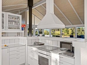 Eine moderne Küche mit weißen Schränken, einem eingebauten Backofen und einem großen Fenster mit Blick ins Freie.