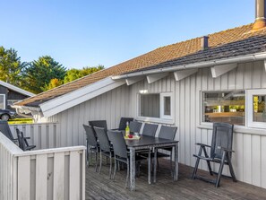 A covered outdoor patio with a table and chairs, a window, and a wooden deck. - "Otta" - 779m from the sea by Interhome (Hjørring)