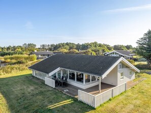 Une maison de plain-pied avec un porche couvert, une terrasse et une pelouse.