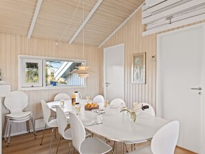 Un coin repas avec une table blanche, des chaises et une fenêtre donnant sur un beau paysage.