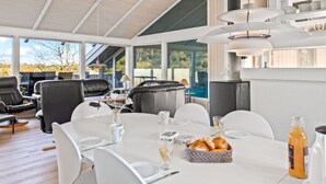 Un comedor moderno con una mesa preparada para dos personas, una cesta de pan y una botella de jugo de naranja.