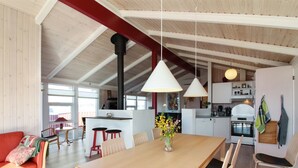A spacious kitchen with modern appliances, a dining area with a wooden table and chairs, and a cozy seating area with a red sofa. - "Skrallan" - 400m from the sea by Interhome (Hjørring)