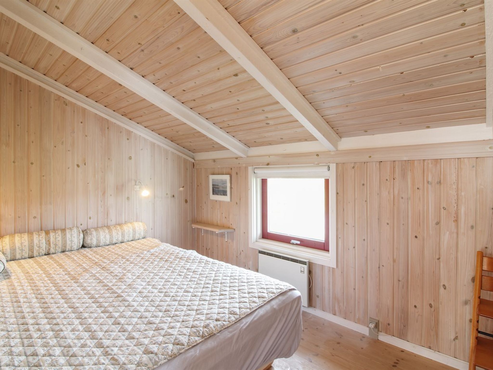 Una camera da letto con un letto, pareti in legno, una finestra e un termosifone.