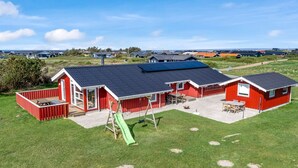 A red building with a black roof, a green slide, and a patio area. - "Skrallan" - 400m from the sea by Interhome (Hjørring)
