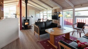 A spacious living area with a high ceiling, a fireplace, comfortable seating, and large windows. - "Skrallan" - 400m from the sea by Interhome (Hjørring)