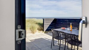 An outdoor patio with a table and chairs, overlooking a beach and the sea. - "Antonie" - 95m from the sea by Interhome (Hjørring)