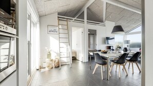 A spacious kitchen with a dining area, a large window, and a high ceiling. - "Antonie" - 95m from the sea by Interhome (Hjørring)