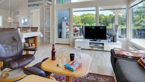 Een ruime woonkamer met een grote televisie, een eethoek met een tafel en stoelen, en een gezellige zithoek met een bank en salontafel.