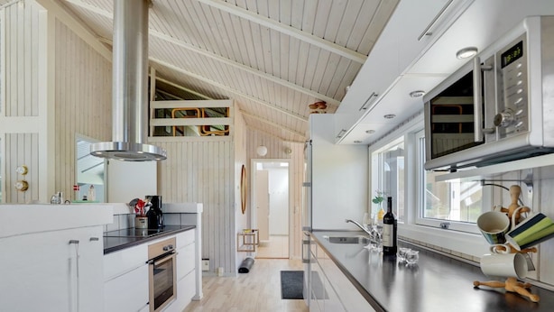 Een moderne keuken met een groot eiland, roestvrijstalen apparatuur en uitzicht op de aangrenzende eetruimte.