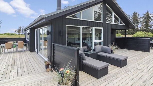 A modern house with a large deck, built-in seating, and a chimney.