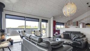 A modern living room with a fireplace, leather sofas, and a large window overlooking a scenic view.