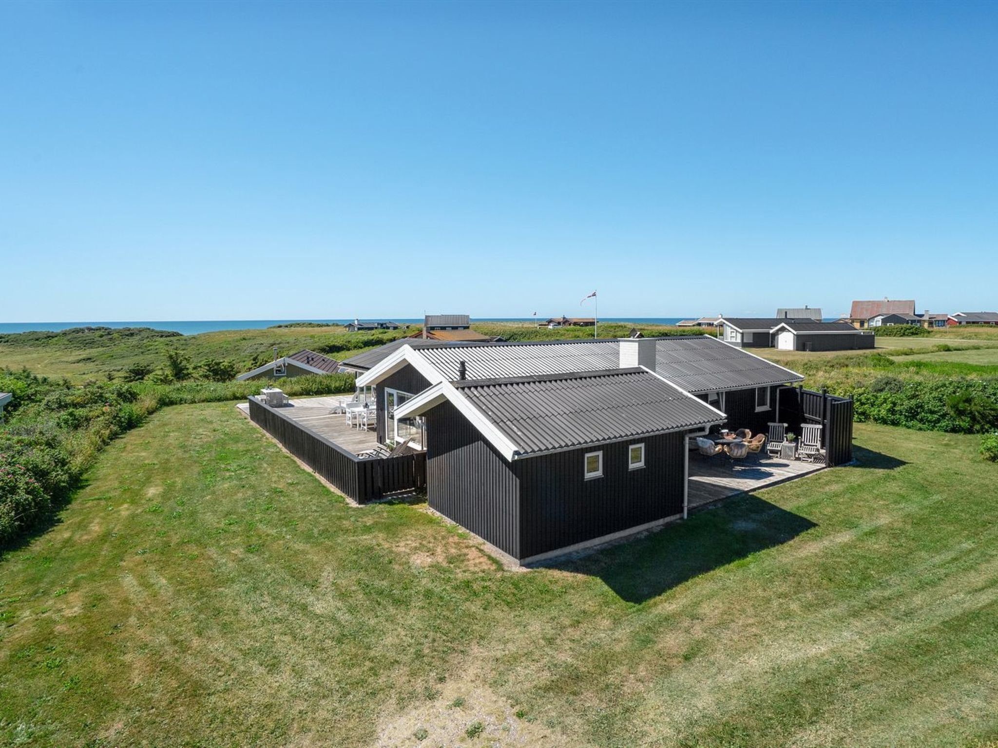 Une propriété située sur la côte, comprenant plusieurs chalets, chacun doté d’une terrasse et offrant une vue sur la mer.