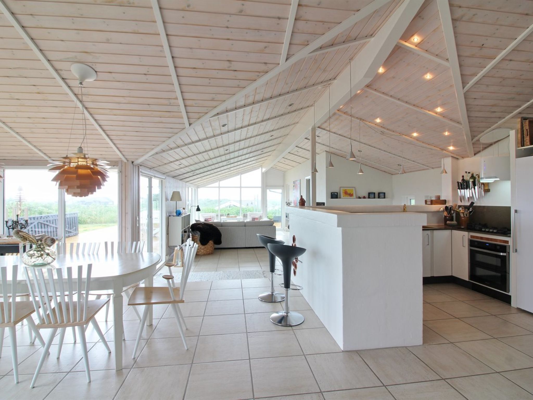 A spacious kitchen with a large island, white cabinetry, and a view to the outdoors.