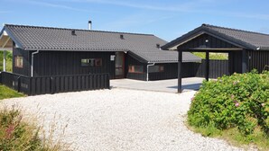 En moderne bygning med grusvej og en overdækket udendørs plads.