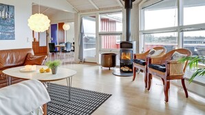 Un salon moderne doté d’une grande fenêtre, d’une cheminée, d’un coin repas et d’un espace salon confortable.