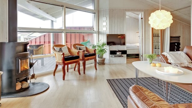 Un salon spacieux doté d’une grande cheminée, de sièges confortables, d’un téléviseur et offrant une vue sur l’extérieur.