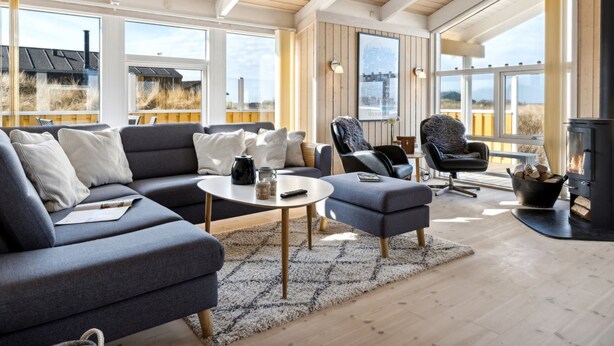 A spacious living room with a large sofa, two armchairs, a coffee table, and a fireplace.