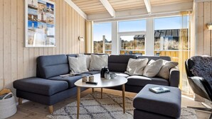 A modern living room with a blue sofa, a round coffee table, and a view of the outdoors through large windows.