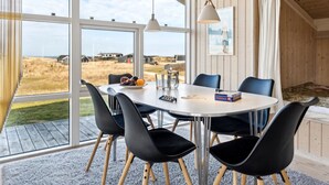 A dining area with a round table, black chairs, and a view of the beach.