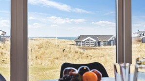 A view from a window overlooking a house in a grassy area with a clear sky.