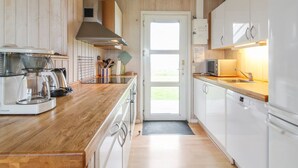 A modern kitchen with wooden cabinets, a stainless steel range hood, and a large window providing natural light.