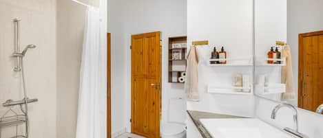 Een moderne badkamer met douche, toilet en wastafel.