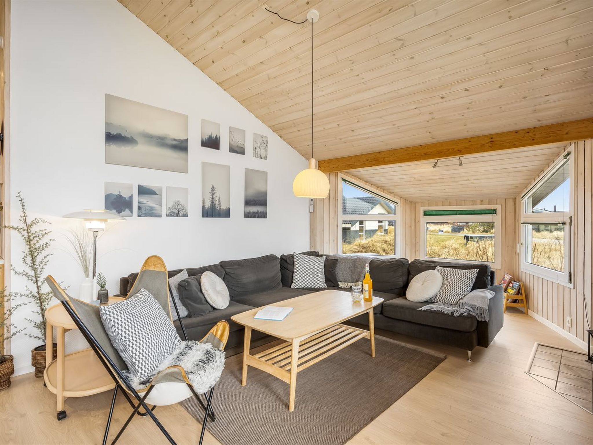 Ein modernes Wohnzimmer mit Holzboden, einer Sofagarnitur, einem Couchtisch und Wandbildern.