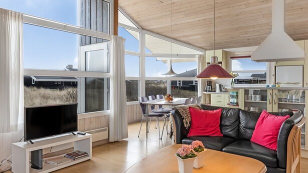 Un salon moderne doté d’un grand téléviseur, de meubles en bois et d’un coin repas avec une table et des chaises.