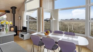 Un intérieur moderne avec une grande fenêtre, une cheminée et un coin repas.