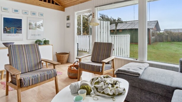 A spacious living room with wooden beams, large windows, and a view of the backyard.