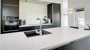 Une cuisine moderne équipée d’un four encastré, d’un évier et d’une machine à café.