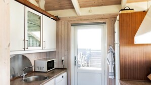 Cocina compacta con armarios blancos, microondas, fregadero y estufa.