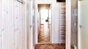 Un pasillo con paredes de madera y suelo de baldosas que conduce a una habitación.