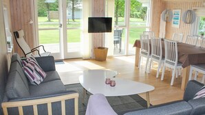 Una sala de estar acogedora con un sofá, una mesa de centro y un televisor. Hay una zona de comedor con sillas y una mesa.