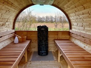 A sauna with wooden benches and a large black sauna stone in the center. - "Suna" - 1.3km from the sea by Interhome (Hjørring)