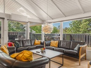 Ein moderner Außenbereich mit Ecksofa, Couchtisch und einer auffälligen geometrischen Leuchte.