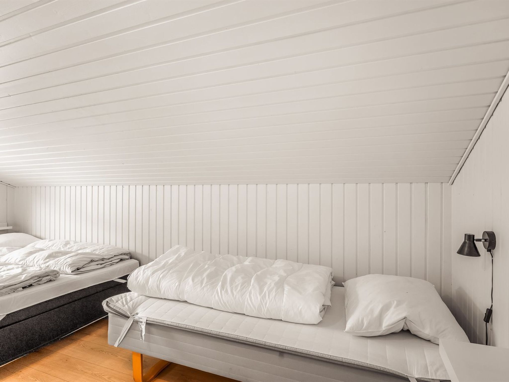 A bedroom with a bed, a bedside table, a lamp, and a window.