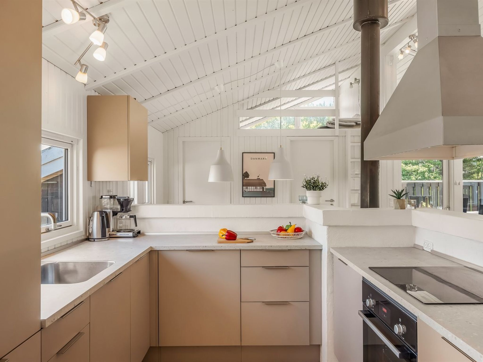 A modern kitchen with a white ceiling, built-in cabinets, a central island, and a large window.