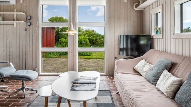 Una sala moderna con sofá, televisión y comedor con mesa y sillas.