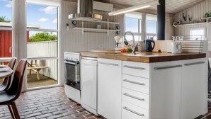 Una cocina moderna con armarios blancos, encimera de madera y campana extractora negra.