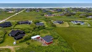 Vista aérea de una zona residencial costera con casas, céspedes verdes y una vista despejada del océano.