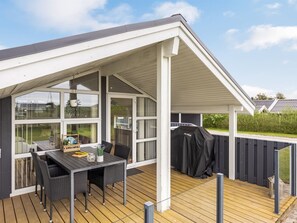 A covered outdoor area with a table and chairs, a grill, and a view of the surrounding landscape. - "Fliri" - 700m from the sea by Interhome (Hjørring)