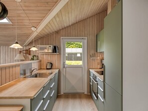 A modern kitchen with wooden paneling, a central island, stainless steel appliances, and pendant lighting. - "Fliri" - 700m from the sea by Interhome (Hjørring)