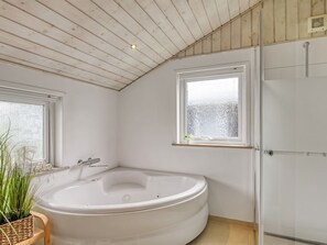 A bathroom with a freestanding bathtub, a glass shower enclosure, and a window with a view of the outside. - "Fliri" - 700m from the sea by Interhome (Hjørring)
