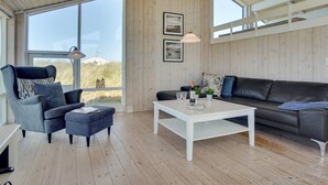 Un salon moderne avec une grande fenêtre, un canapé, une table basse et un fauteuil.